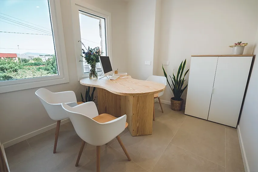 Sala de consulta y asesoramiento de la Clínica Dentalcom, con mesa de madera y ventana al exterior