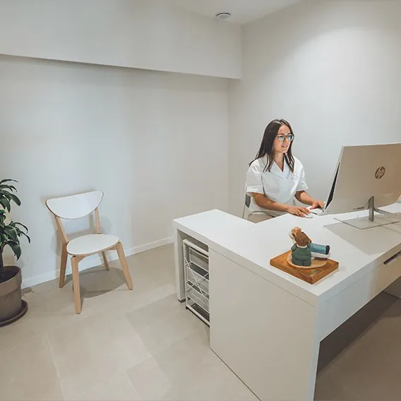 Recepcionista de la Clínica Dentalcom atendiendo en el mostrador de recepción