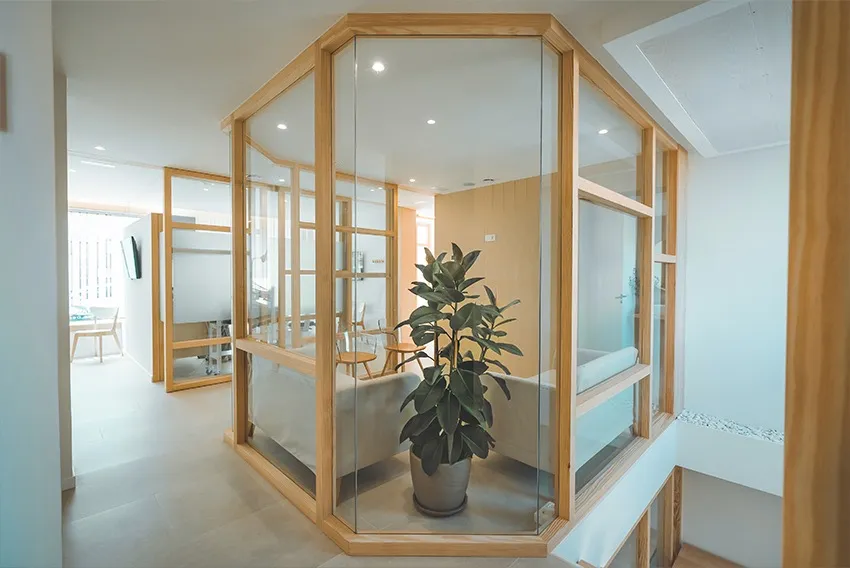 Interior de la Clínica Dentalcom con una cabina acristalada de madera y acabados naturales